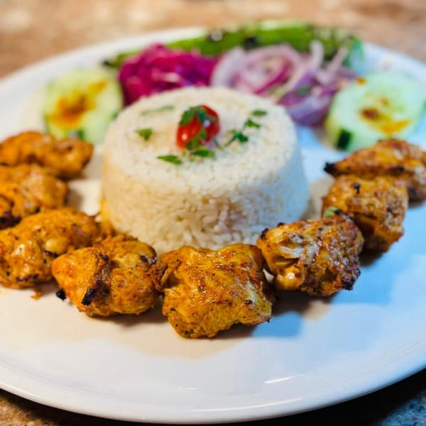 Koy Grill's Mediterranean chicken shish tawook with rice, pickled onions, and cucumber slices.