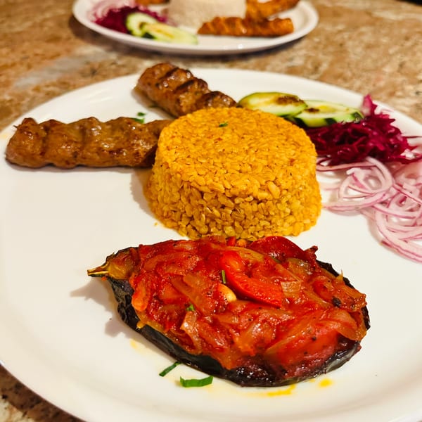 Koy Grill's Mediterranean dish with grilled meat, bulgur, stuffed eggplant, and pickled vegetables.