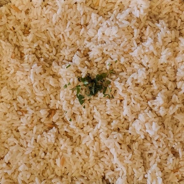Close-up of fluffy white rice, lightly seasoned with fresh green herbs, a side dish at Koy Grill.