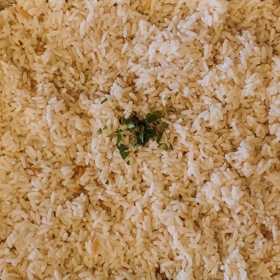 Close-up of fluffy white rice, lightly seasoned with fresh green herbs, a side dish at Koy Grill.