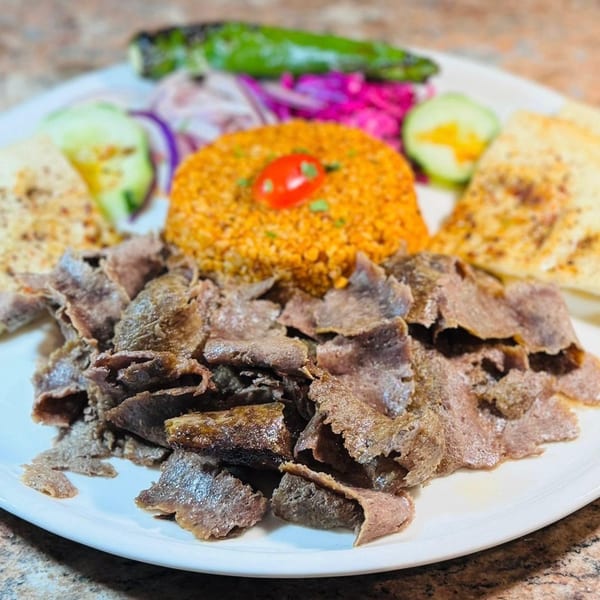 Koy Grill's Mediterranean dish with sliced meat, rice, pita bread, and pickled vegetables.